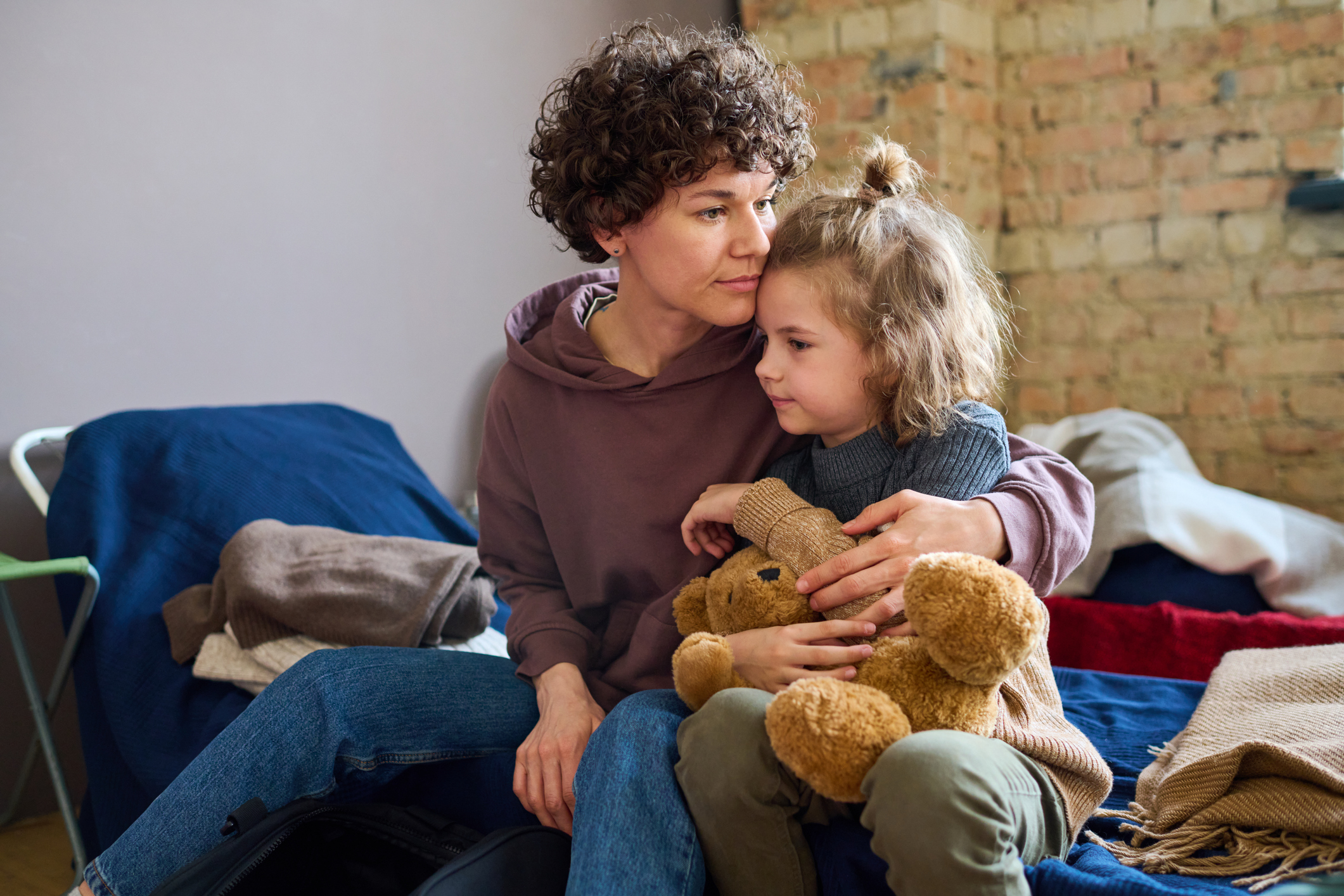 A woman with her arm around her child in a shelter.