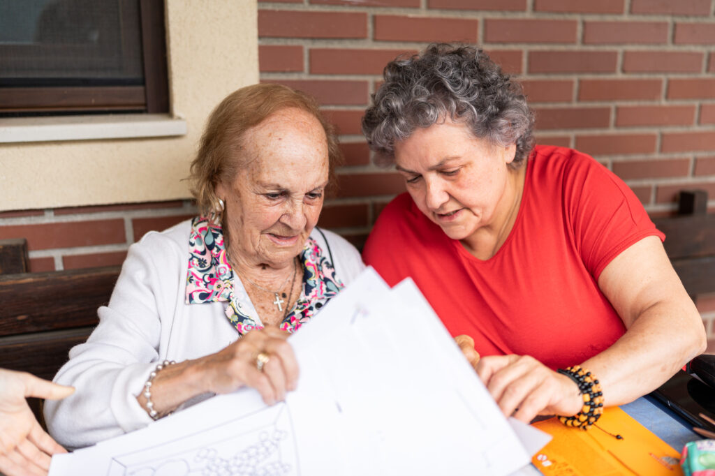 Woman helping an elderly woman and holding papers.